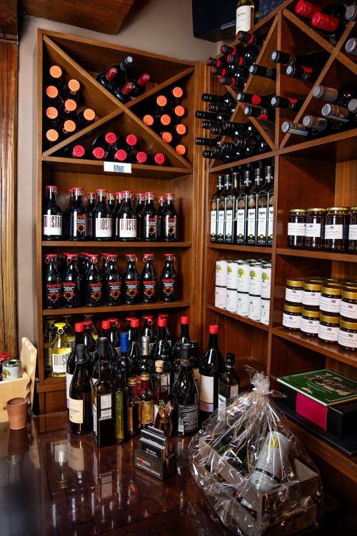 griechische-feinkost-weinregal-restaurant-der-grieche Wein- und Feinkostregal im Restaurant „Der Grieche unter den Linden“ mit griechischem Wein, Olivenöl, Honig und Spezialitäten.